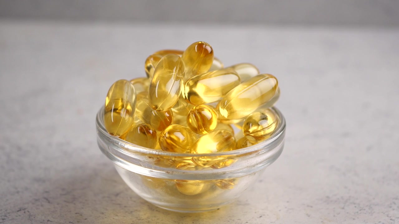 Close-up of Yellow Softgel Capsules in a Glass Bowl
