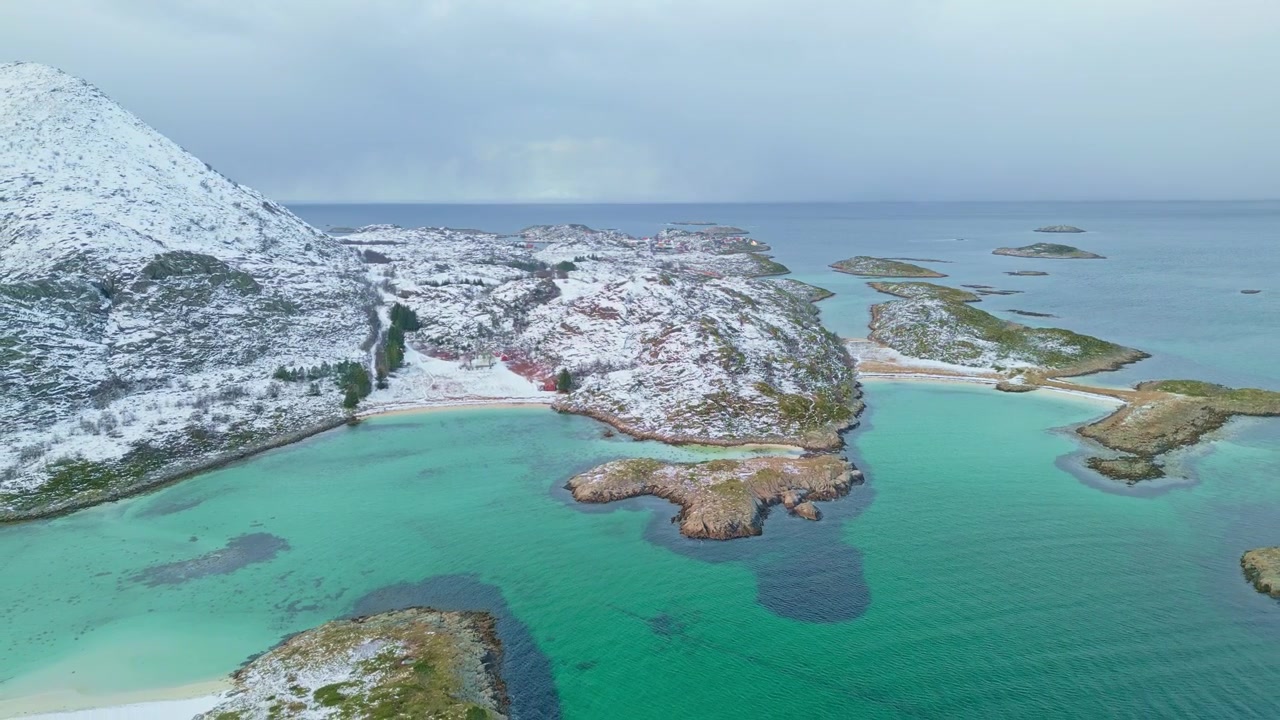 Vista costeira nevada de Lofoten, Noruega, com mar turquesa e ilhas rochosas.