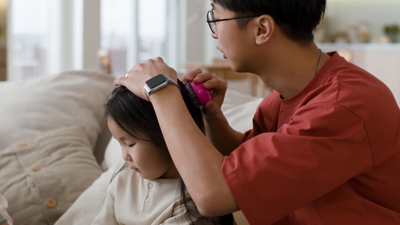 Father brushing daughter's hair at home