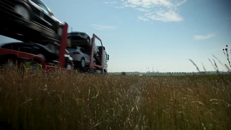 Low-angle-shot-of-a-car-carrier-truck-speeding-along-a-country-road,-sunny-day