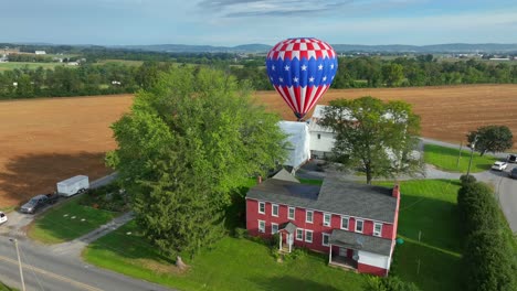 Luftaufnahme-Eines-Amerikanischen-Bauernhauses-Mit-Landendem-Heißluftballon-Auf-Einem-Feld-Im-Hintergrund---Lancaster,-Pennsylvania,-USA