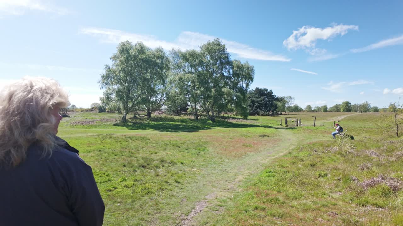 mujer caminante observando a lo largo del campo sanderling sendero camino suffolk