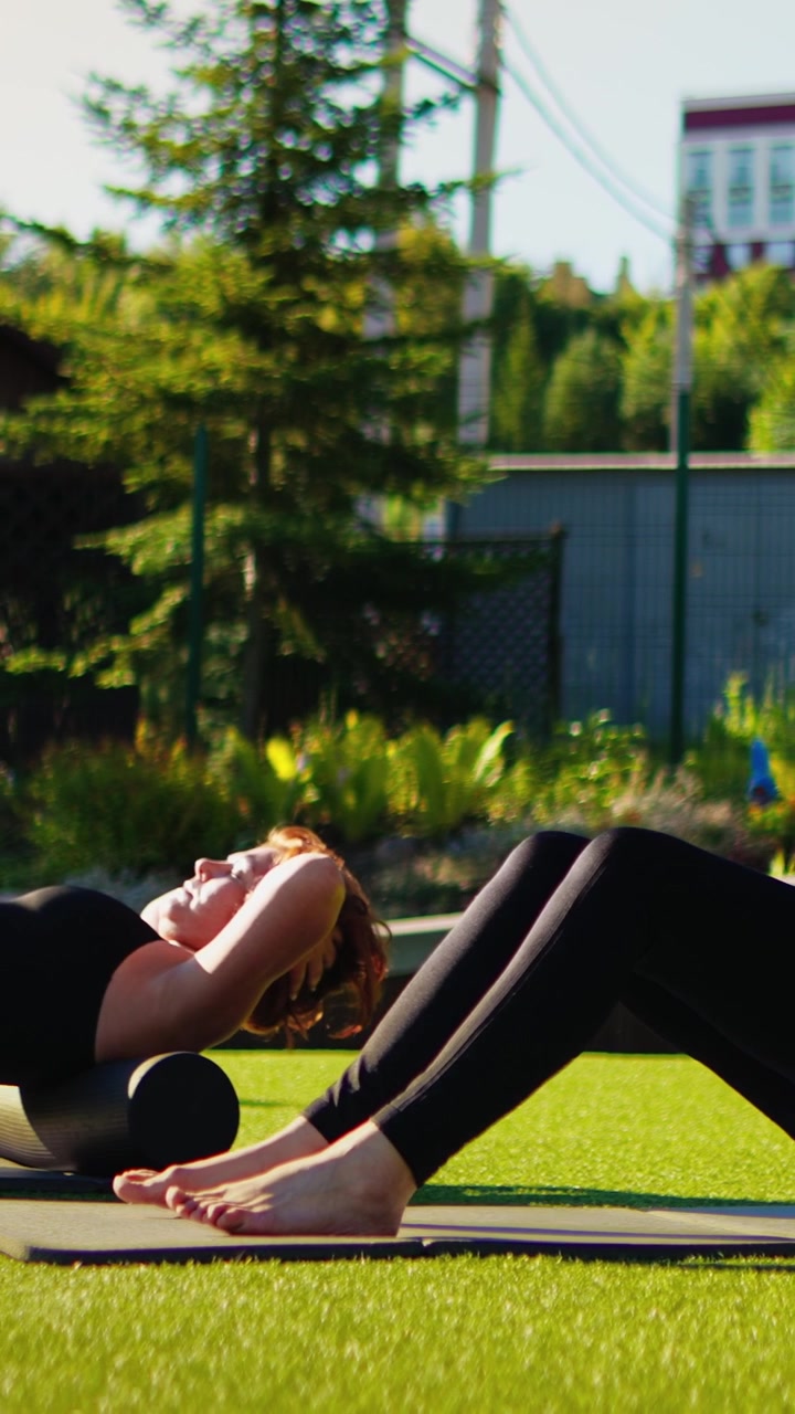 Donna che usa un foam roller per un massaggio alla schiena all'aperto