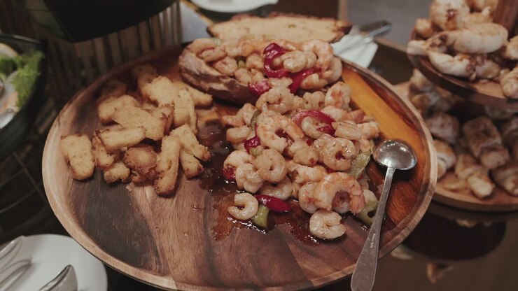 Rejer sauteret med peberfrugter serveret med stegt brød på et rustikt fad ved buffetbordet