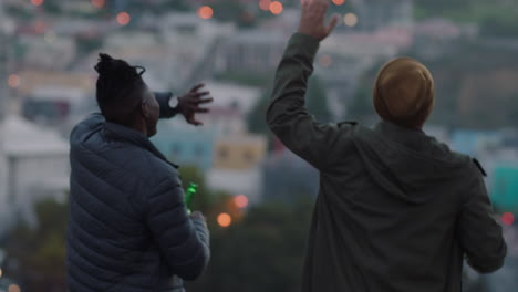 happy friends dancing on rooftop having fun enjoying hanging out at sunset drinking refreshing beer sharing view of city skyline