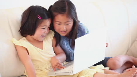 Two-girls-laughing-as-they-use-a-laptop-together