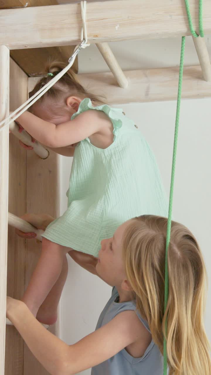 Older Sister Helps Younger Girl Climb Down Wooden Ladder