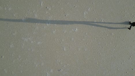 long shadow of person or silhouette walking on surface of dried salt lake