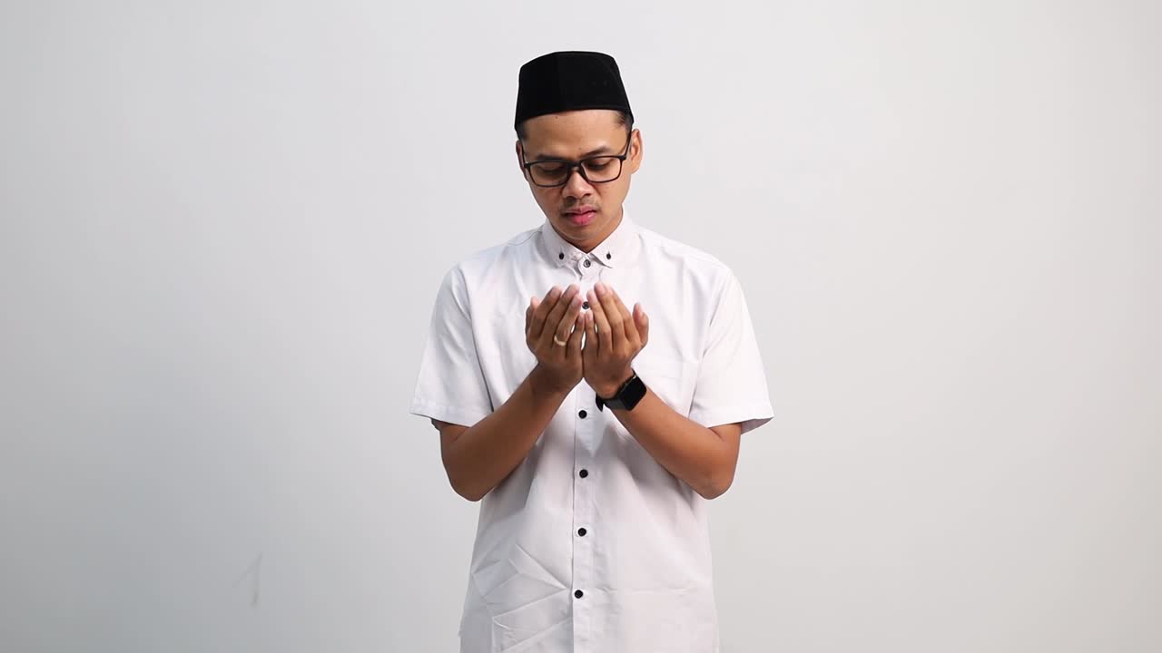 Muslim man raises his hands in a prayer gesture