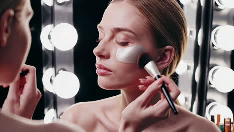 makeup artist applying face mask to model