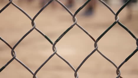 kickball rolls by in background of fence