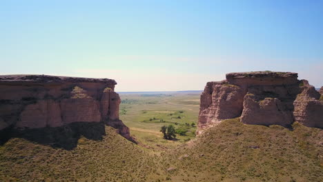 Aerial-fly-between-2-rock-mesas-towards-farmland-in-central-Wyoming