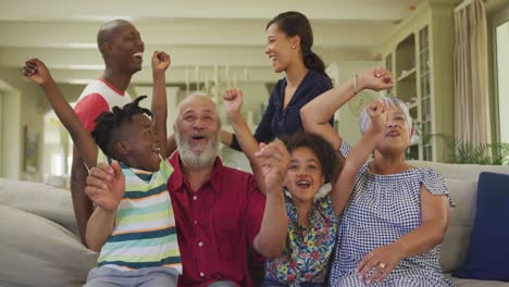 Three-generation-family-cheering-while-watching-TV-at-home