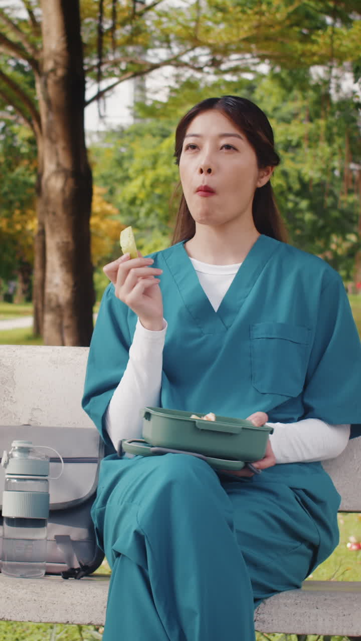Female Doctor Eating from Lunch Box in Park