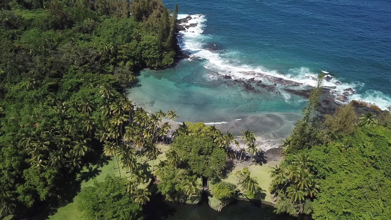 Praia de areia preta na Big Island, Havaí, com ondas quebrando nas rochas