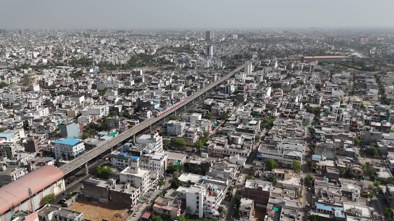 Overhead shot capturing Jaipur's urban complexity where metro train passes through the city
