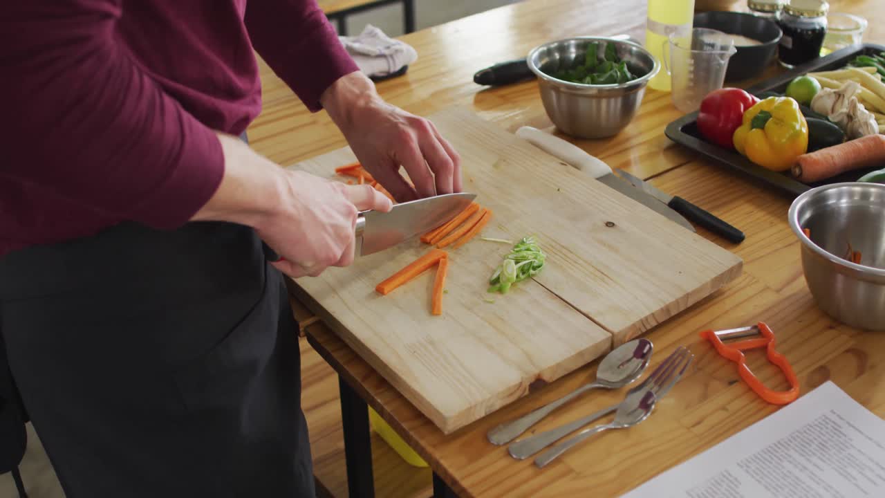 cocinero caucásico cortando zanahorias en la cocina