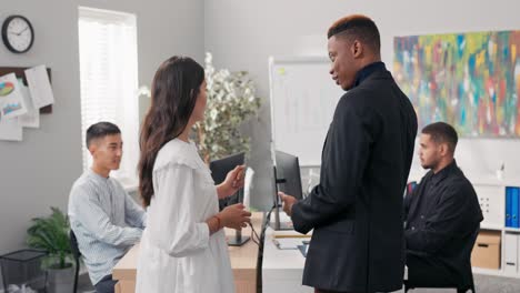 el jefe elegantemente vestido felicita al empleado ambicioso y talentoso por su ascenso delante de todos los compañeros de trabajo, elogia a la mujer, le estrecha la mano, intercambian sonrisas