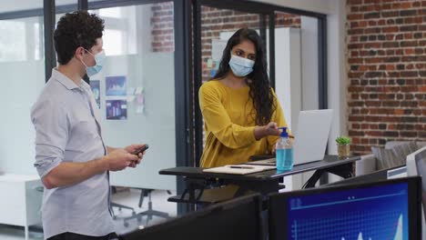 hombre y mujer con máscaras faciales trabajando juntos en la oficina