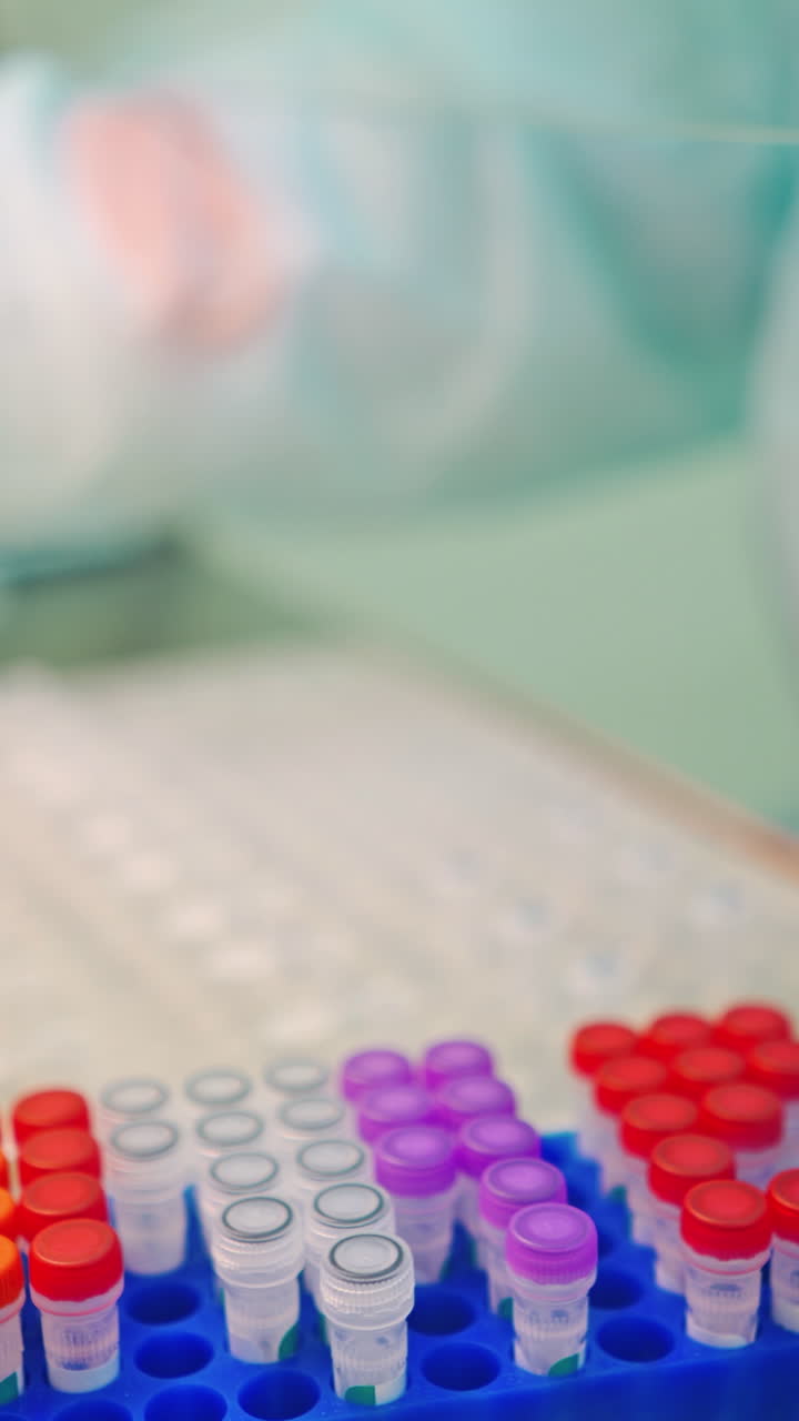 Test tubes on a rack on the laboratory table. Medical assistant in protective uniform and gloves working with vials of samples in scientific clinic. Vertical video