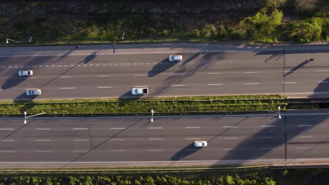 antena: concurrida autopista de varios carriles rodeada de vegetación verde al borde de la carretera - hermoso clima con luz solar - vista de arriba hacia abajo