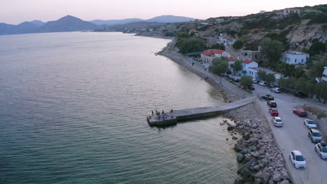 Aerial-orbits-people-enjoying-sunny-evening-on-pier-in-Aegean-Sea,-GRC