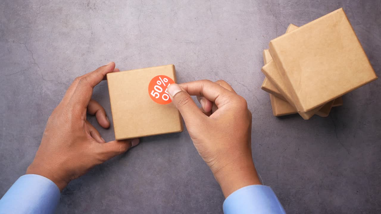 la aplicación de una pegatina de descuento a una caja de regalos