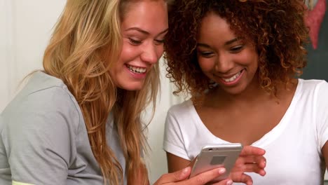 dos amigas jóvenes sonrientes leyendo un mensaje de texto