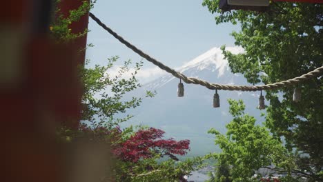 dolly reveal of shimenawa across torii gate with snow capped mount fuji in distance on sunny clear day