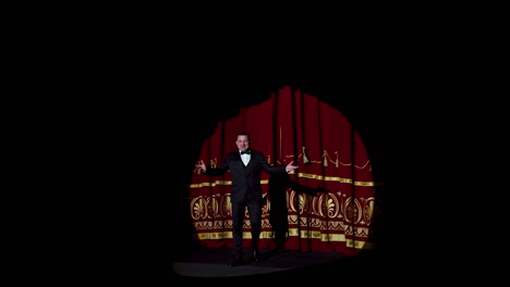 actor appears on stage. red curtains open and a theater host in suit comes on the scene on dark background in light spot.