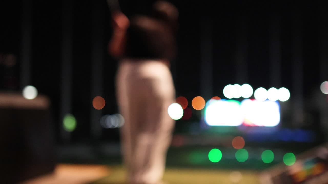 Person practicing golf swing at night range