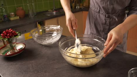 slow zoom-in close up shot of a young woman mixing the egg white foam into the mixture of butter and honey preparing a honey cake filling