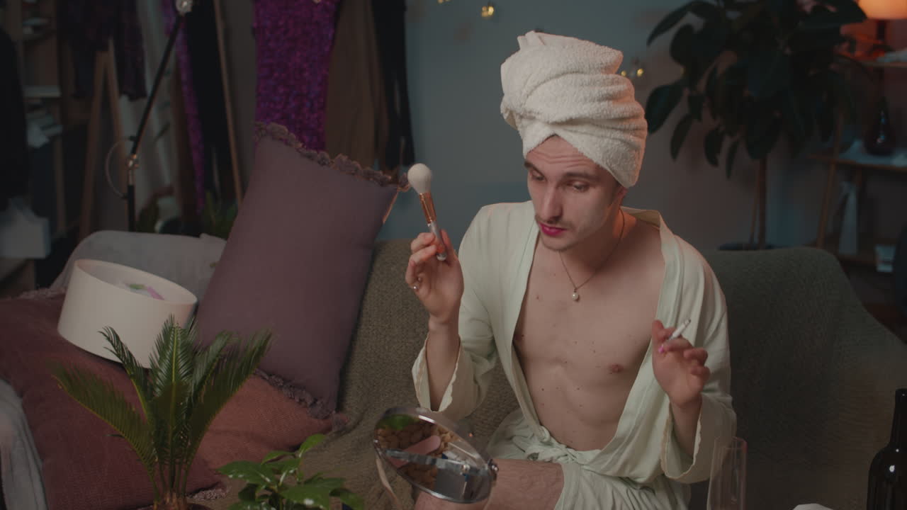 Man applying makeup with towel on head