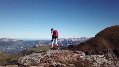 excursionista macho adulto con mochila llegando al mirador de la montaña en suiza