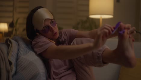 woman doing foot care while on the phone at home at night