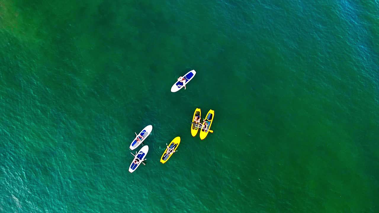 Un gruppo di giovani amici sui paddle board sull'acqua, ripresa con drone