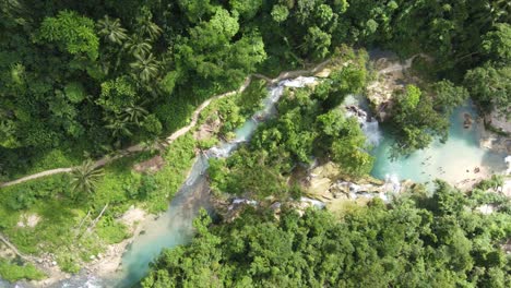 Río-Matutinao-Que-Fluye-A-Través-De-Un-Frondoso-Bosque-Que-Alimenta-Las-Cataratas-Kawasan,-Antena-Arriba-Hacia-Abajo