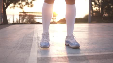 primer plano de las piernas de una jugadora de baloncesto con calcetines de golf blancos haciendo ejercicio de goteo muy rápido, correr hacia atrás, entrenar al aire libre en la cancha local 1