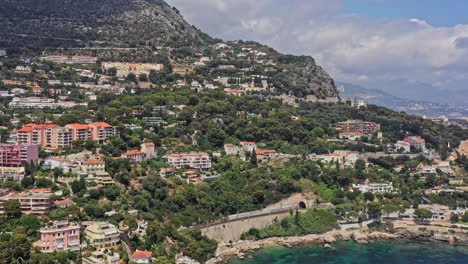 cap d'ail france aerial v2 establishing pan right shot capturing hillside residential buildings and resorts, reveals beautiful mediterranean sea on a sunny day - july 2021