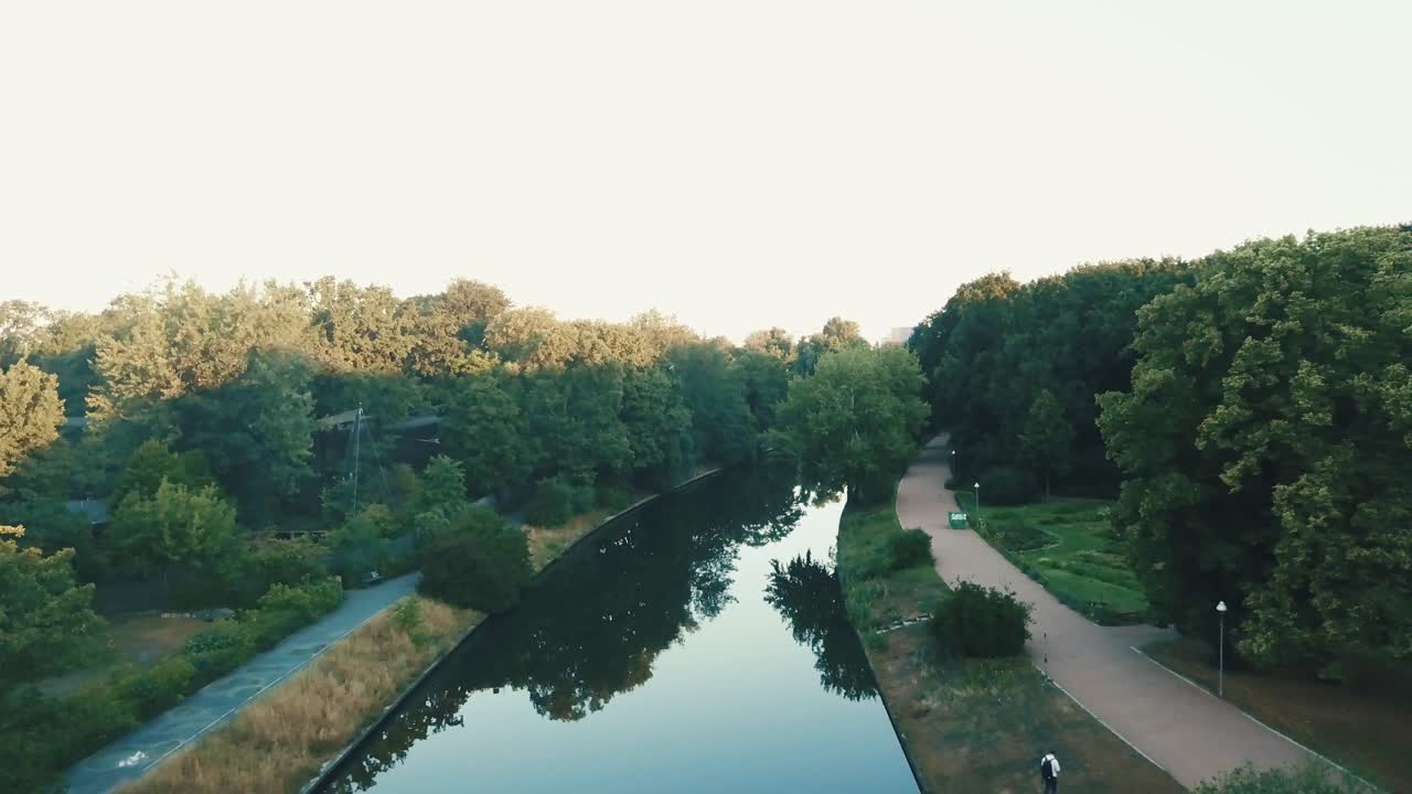 물이 반사되는 일출 동안 나무가 있는 아름다운 공원의 강 위에 드론 공중