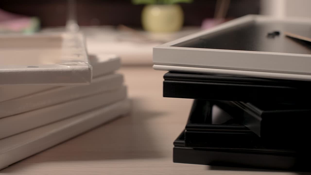 Pile of art canvases and frames on a desk
