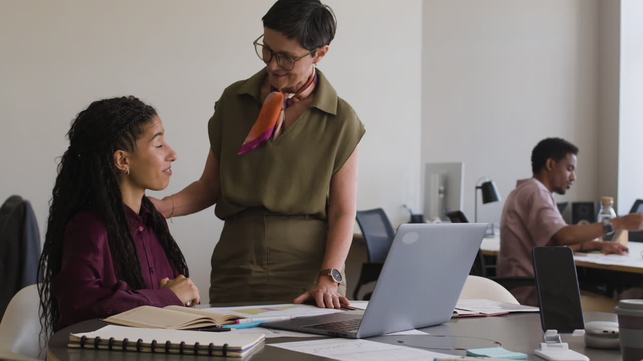 Two women collaborating and discussing work in a modern office