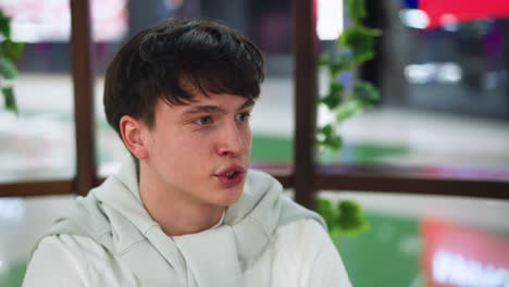 young adult with brown hair taking bite of fries, wounded looking lips visible, closeup showing expression of pain and hunger, greasy fingers holding crispy potato sticks, background blurred