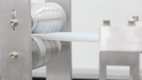 máquina de fábrica con herramientas que hacen pliegues de ondulación en tela - fabricante de máscara protectora - primer plano, cámara lenta