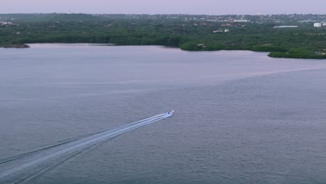 boat drives up into harbor leaving large rounded wake behind on cloudy day