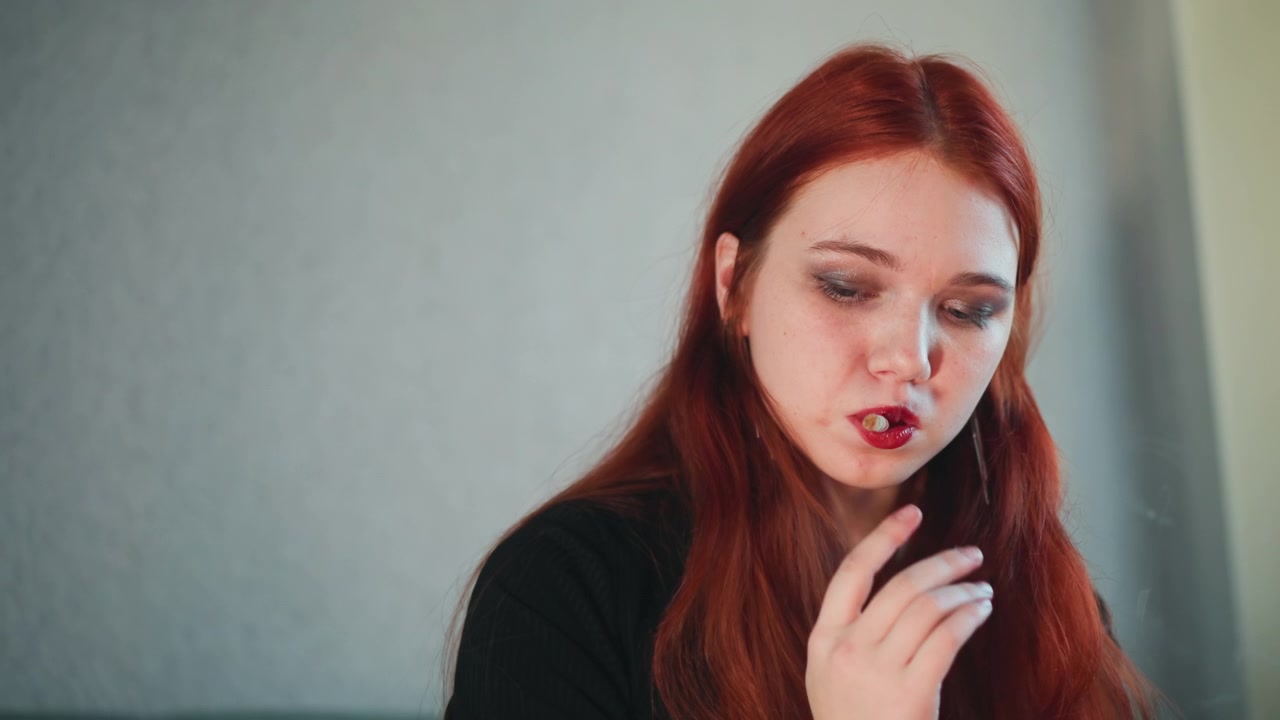 Caucasian redhead woman covers mouth in shock after tarot reading, sits in quiet studio, touches lips, eyes downcast, expressions shift from surprise to pensive worry, mood tense mystical, hints