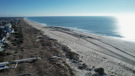 Drone-shot-of-beach-nourishment,-or-adding-sand-or-sediment-to-beaches-to-combat-erosion,-can-have-negative-impacts-on-wildlife-and-ecosystems,-with-water-coming-out-of-pipe