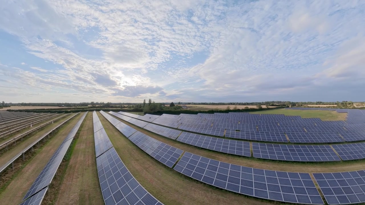 Droneoptagelse fra luften, solnedgang over et felt med vedvarende energikilder med vindmøller og naturligt landskab. Solcelleanlæg, vindmøller og landskab i Lincolnshire, England.