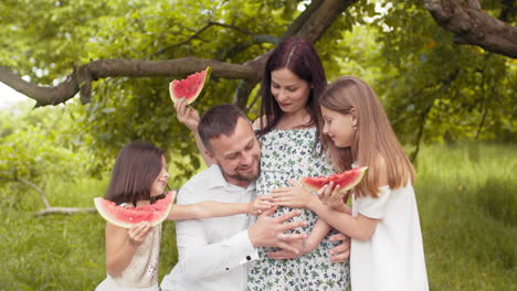 happy family enjoying watermelon in a park