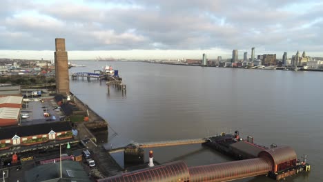 Woodside-ferry-village-terminal-aerial-orbit-left-across-Birkenhead-Liverpool-harbour-skyline-and-River-Mersey